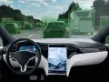 Widok z kabiny samochodu z włączonym autopilotem. System rozpoznaje inne pojazdy na drodze, oznaczając je zielonymi ramkami i kierunkiem jazdy.