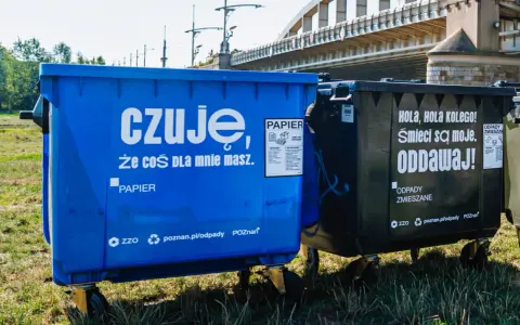 Niebieski kontener na makulaturę z napisem "czuję, że coś dla mnie masz. PAPIER" obok czarnego na odpady zmieszane.
