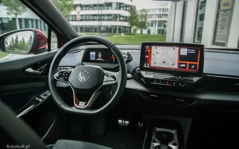 Wnętrze Volkswagena ID.4 GTX z ekranem nawigacji i cyfrowym kokpitem. Kierownica z przyciskami i oznaczeniem GTX.