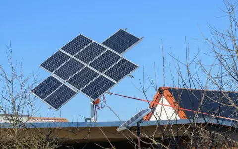 System paneli fotowoltaicznych z trackerem PV, zamontowany na dachu domu, na tle błękitnego nieba.