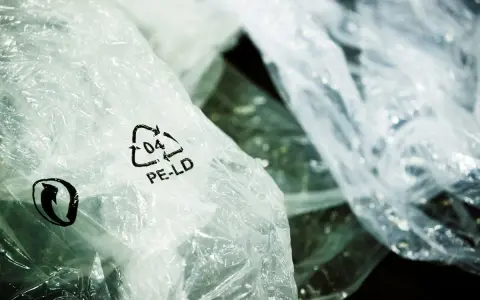 Zgniecione folie PE-LD z symbolem recyklingu. Firma stawia na recykling tworzyw sztucznych, dbając o środowisko.