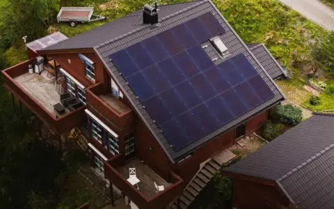 Dom z tarasem i przyczepką, na dachu którego zamontowano panele fotowoltaiczne. Ta mikroinstalacja fotowoltaiczna zapewnia czystą energię.