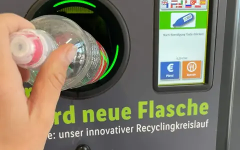 Ręka wrzuca butelkę do automatu. Niemiecki system kaucyjny działa sprawnie, zwracając 0,25 EUR za każdy zwrot.