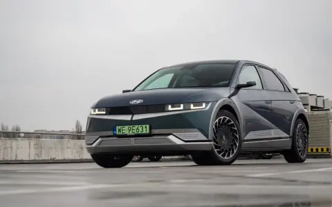 Hyundai Ioniq 5, z charakterystycznymi światłami i felgami, prezentuje swoje imponujące wymiary na mokrym parkingu.